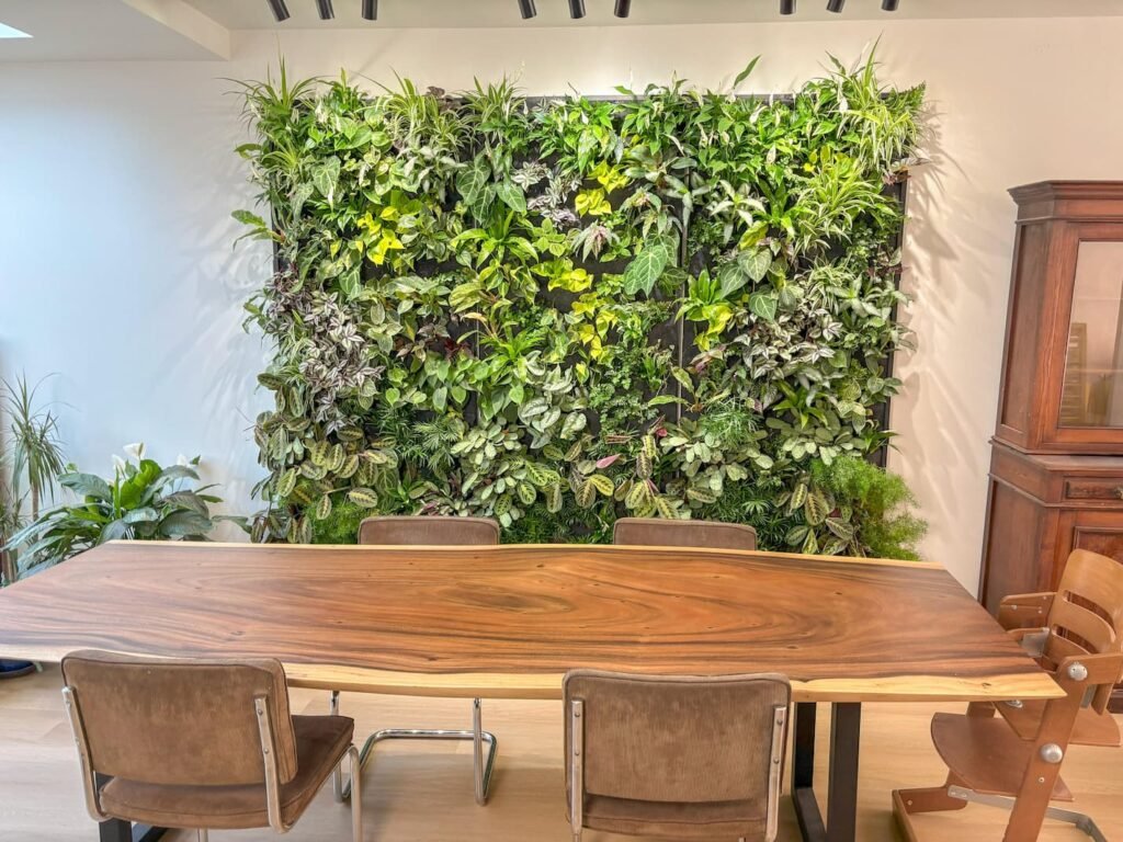 Plantenwand met veel groene planten naast een eettafel
